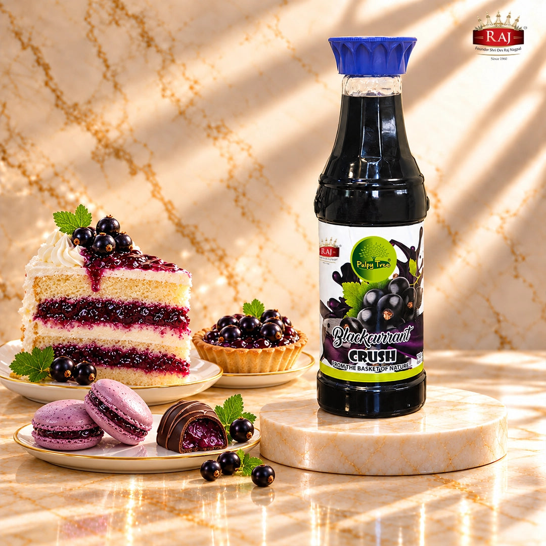 RAJ Pulpy Tree Blackcurrant Crush bottle with berry-filled layer cake, fruit tart, macarons and chocolate.