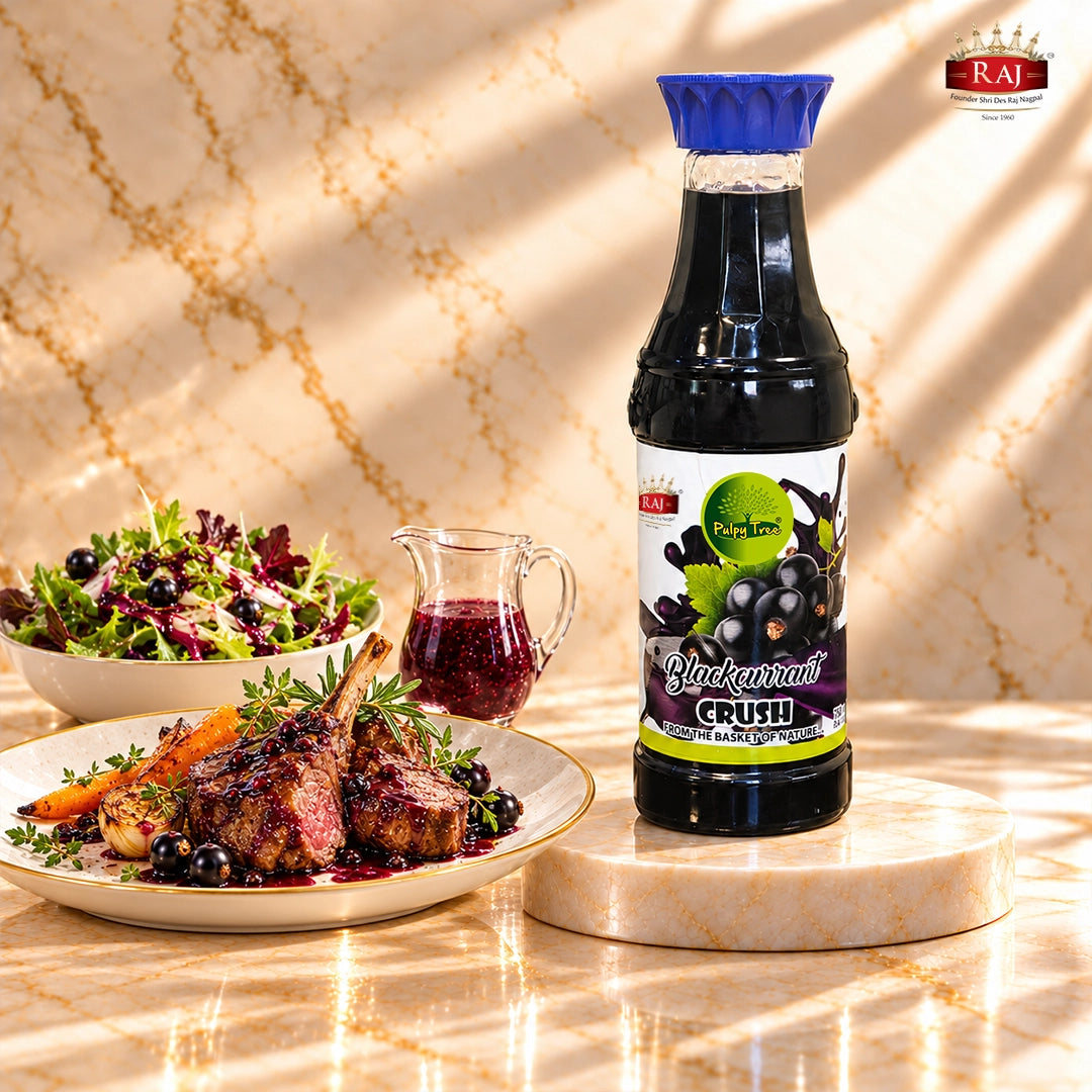 RAJ Pulpy Tree Blackcurrant Crush bottle beside glazed roast lamb and a leafy salad with blackcurrant dressing.
