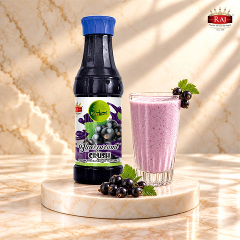 RAJ Pulpy Tree Blackcurrant Crush bottle with blackcurrant milkshake and fresh berries on a marble podium