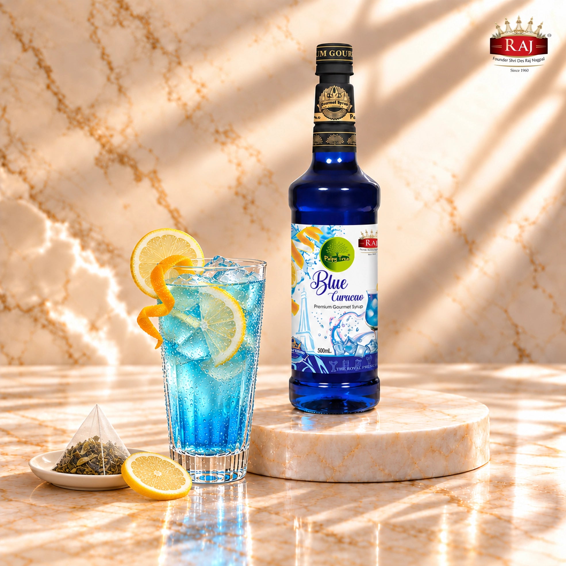 RAJ Pulpy Tree Blue Curacao syrup bottle beside blue citrus iced tea with lemon and a tea sachet.