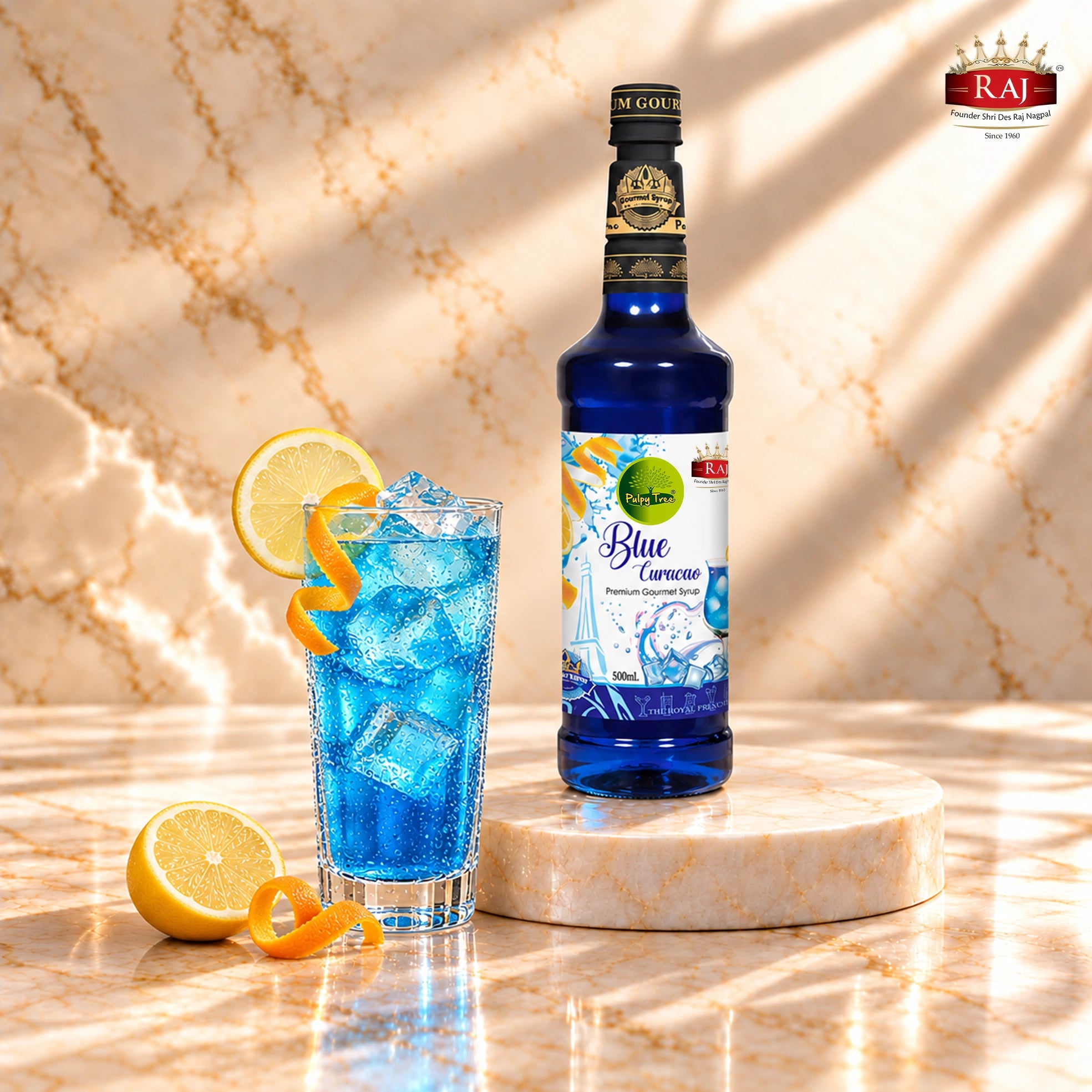 RAJ Pulpy Tree Blue Curacao syrup bottle beside a blue lemonade cooler with ice, lemon slices and a lemon squeezer.