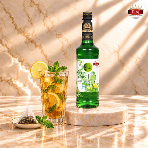 RAJ Pulpy Tree Green Mint syrup bottle beside mint iced tea with lemon, ice and a tea sachet.
