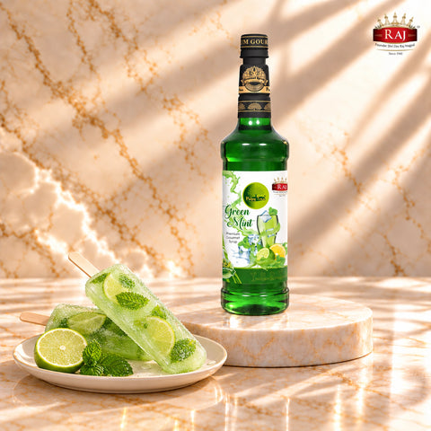 RAJ Pulpy Tree Green Mint syrup bottle beside mint lime popsicles with mint leaves and lime slices frozen inside.