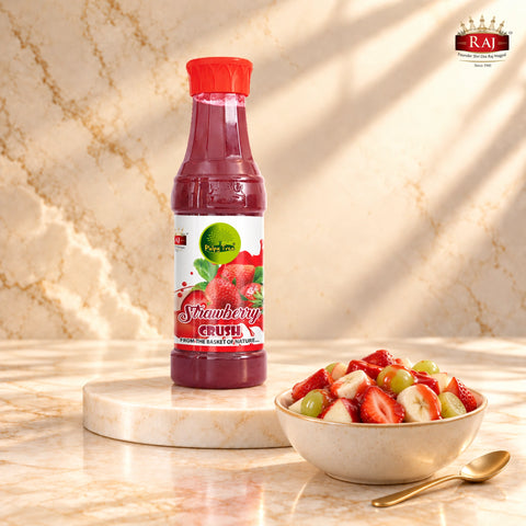Strawberry Crush bottle beside a fruit salad with apple, banana, grapes and strawberry drizzle